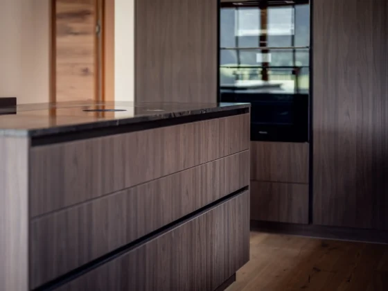 Moderne Küche mit maßgefertigten Holzfronten und schwarzer Arbeitsplatte im Gesamtkonzept von M Studio Reiter Altenmarkt