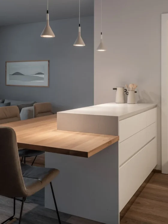Moderner Wohnraum mit maßgefertigter Kücheninsel aus Holz und Weiß, grauem Sofa, Essbereich und, Zweitwohnsitz