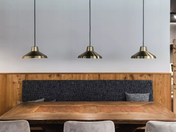 Essbereich mit rustikalem Holztisch, gepolsterter Sitzbank, drei goldfarbenen Hängelampen und Holzvertäfelung, Poliform