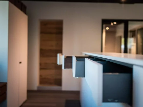 Offene Schubladen einer modernen weißen Kücheninsel in einem Innenraum mit Holzfußboden und minimalistischer, Poliform