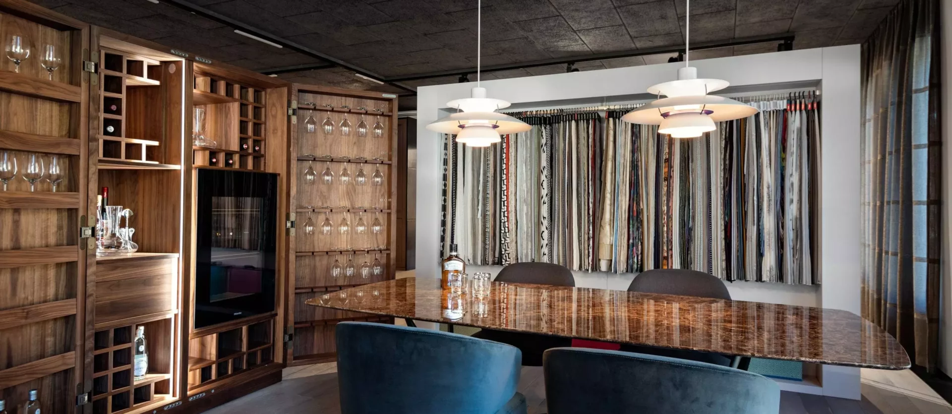 Moderner Showroom mit maßgefertigtem Holzmöbel, Poliform Tisch, Minotti Stühlen, Kartell Lampen und Stoffmustern von