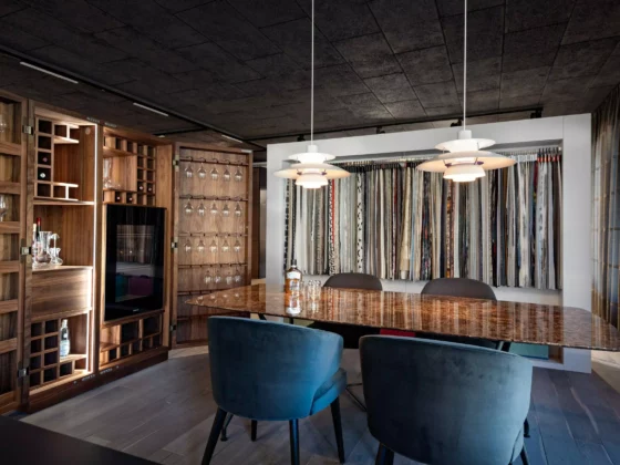 Moderner Showroom mit maßgefertigtem Holzmöbel, Poliform Tisch, Minotti Stühlen, Kartell Lampen und Stoffmustern von