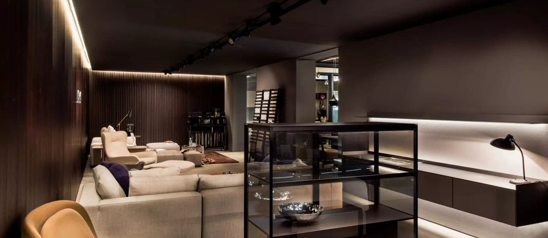Moderner Showroom mit Designermöbeln wie Sesseln, Sofas und Vitrinen in warmem Licht, Innenarchitektur M-Studio Reiter