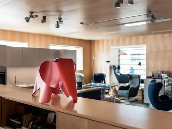 Moderner Showroom mit Designermöbeln, rotem Elephant-Objekt im Vordergrund, Sitzgruppen und Holzverkleidung, Innenarchitekt