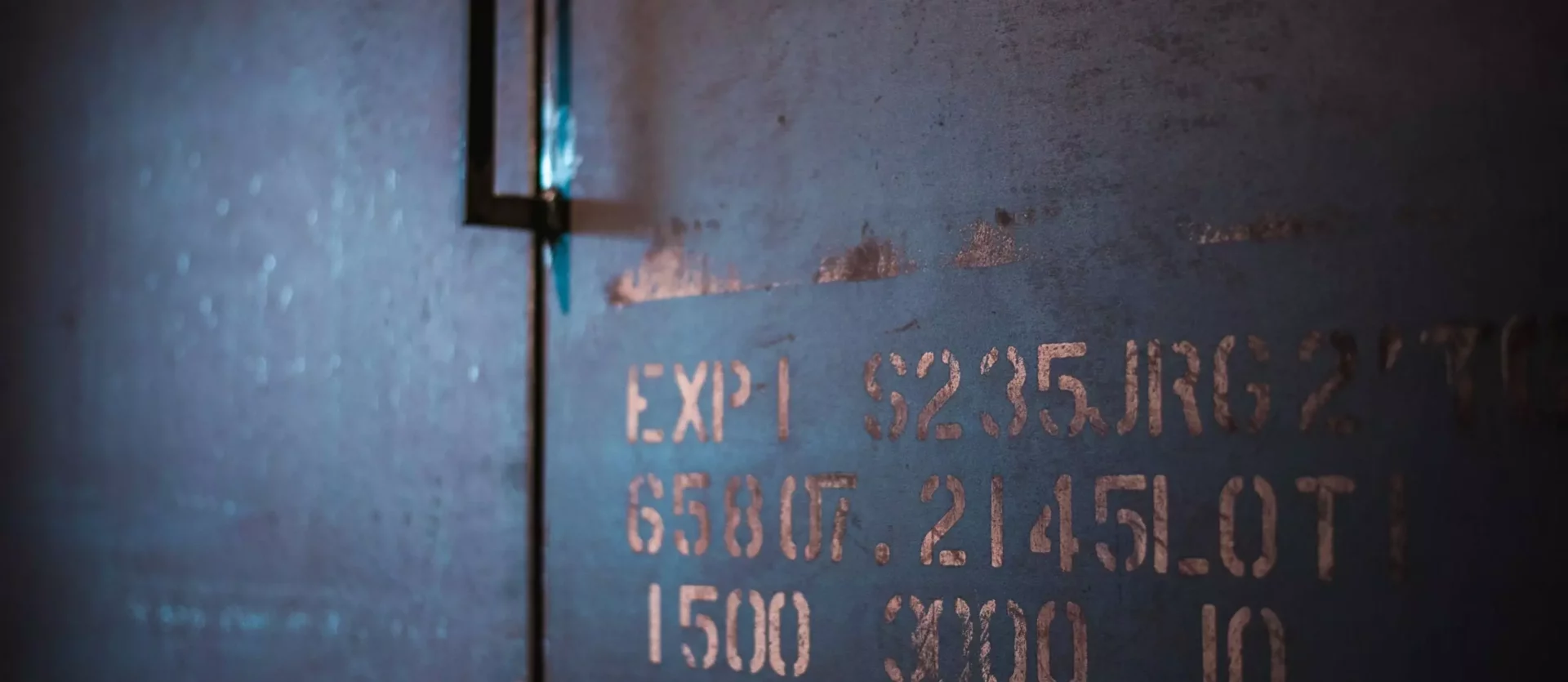 Nahaufnahme einer blauen Metallfläche mit verblasster, rostiger Beschriftung und einem schwarzen Griff, Innenarchitekt