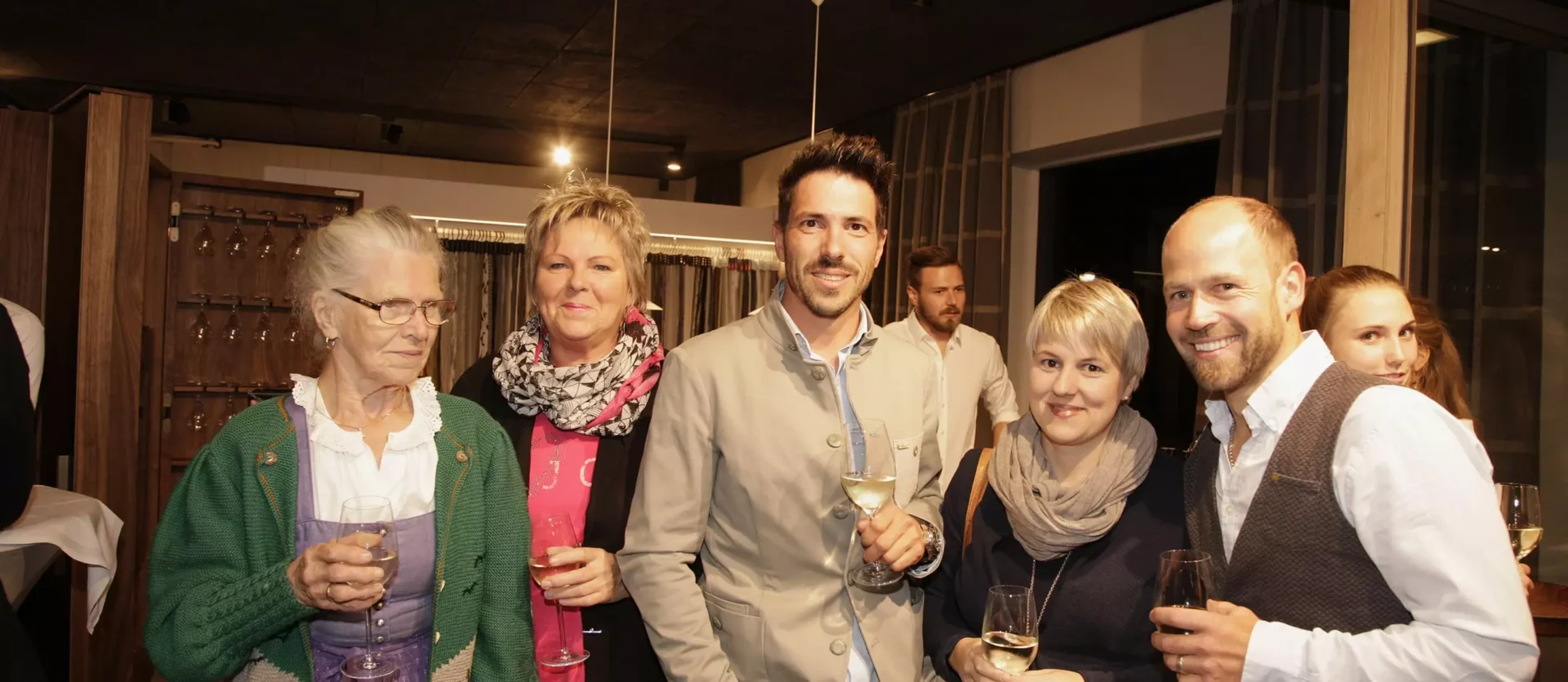 Gruppe von sechs Personen mit Getränken in einem modernen Showroom für Innenarchitektur und Designermöbel von Minotti, Fest