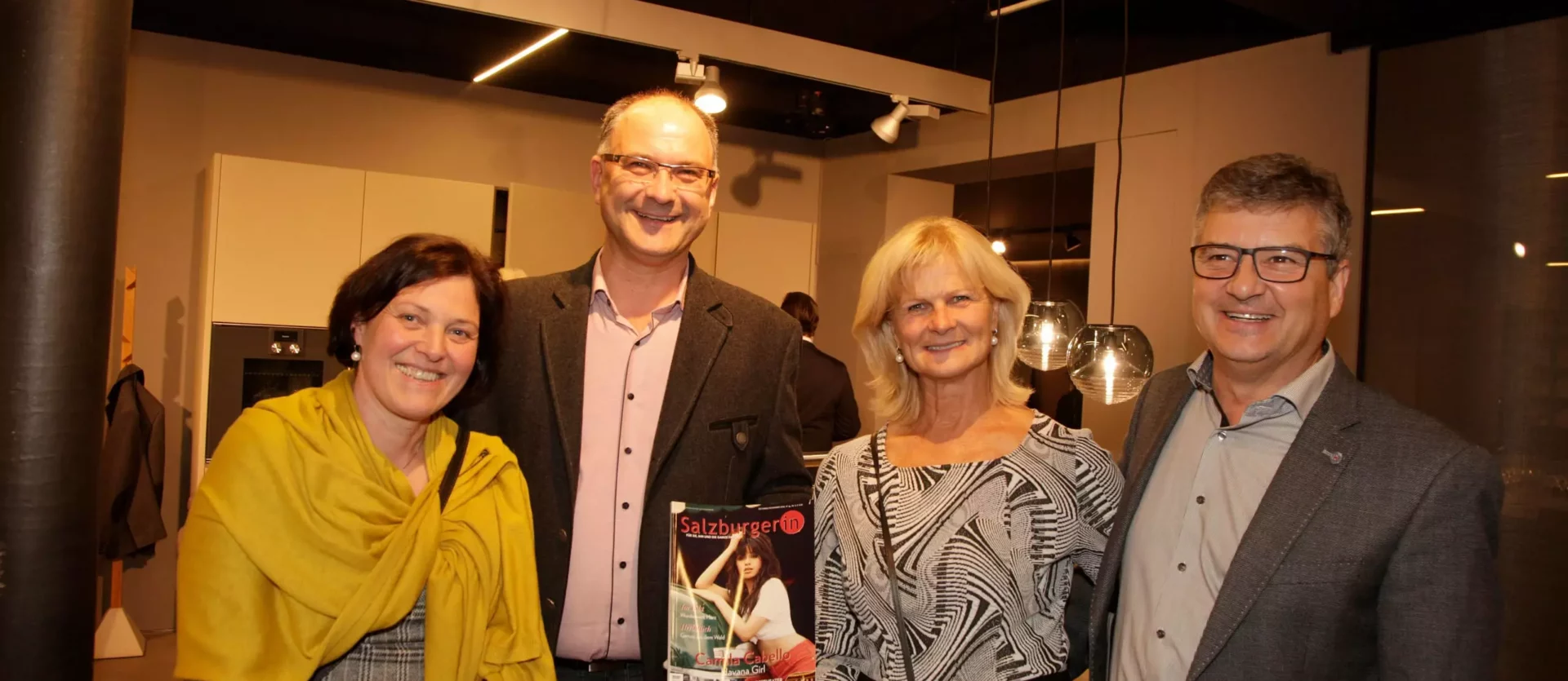 Vier Personen in einem modernen Showroom für Innenarchitektur und Möbel, zwei Männer und zwei Frauen, einer hält eine, Fest