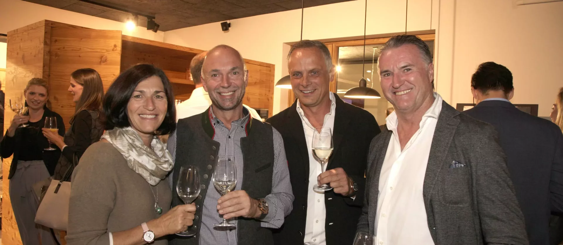 Vier Personen mit Wein in der Hand in einem modernen Showroom für Innenarchitektur und Designermöbel von Minotti, Fest