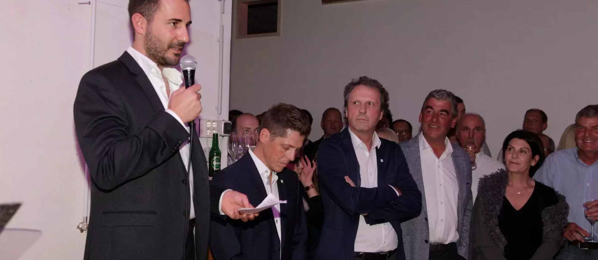 Mann in Anzug hält Mikrofon und spricht vor Publikum bei Veranstaltung im Möbelstudio Showroom von Studio Reiter mit, Fest