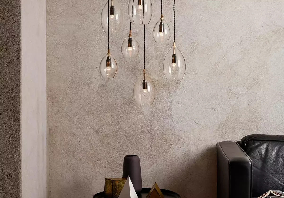 Minimalistischer Wohnraum mit sieben hängenden Glaskugel-Pendelleuchten, schwarzem Beistelltisch mit Dekoobjekten und, Möbel