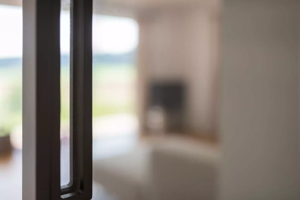 Nahaufnahme einer schwarzen Griffleiste einer Rimadesio Schiebetür mit unscharfem Blick auf modernes Wohnzimmer mit Sofa und