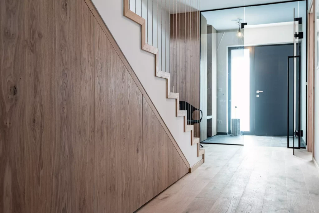 Moderner Eingangsbereich mit maßgefertigter Holztreppe und integrierter Raumlösung in einem Möbelstudio in Altenmarkt