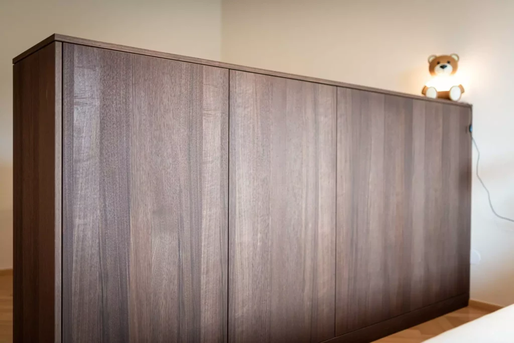 Maßgefertigter Sideboard aus dunklem Holz von Riva1920 mit beleuchtetem Teddybär im Wohnraum in Salzburg.