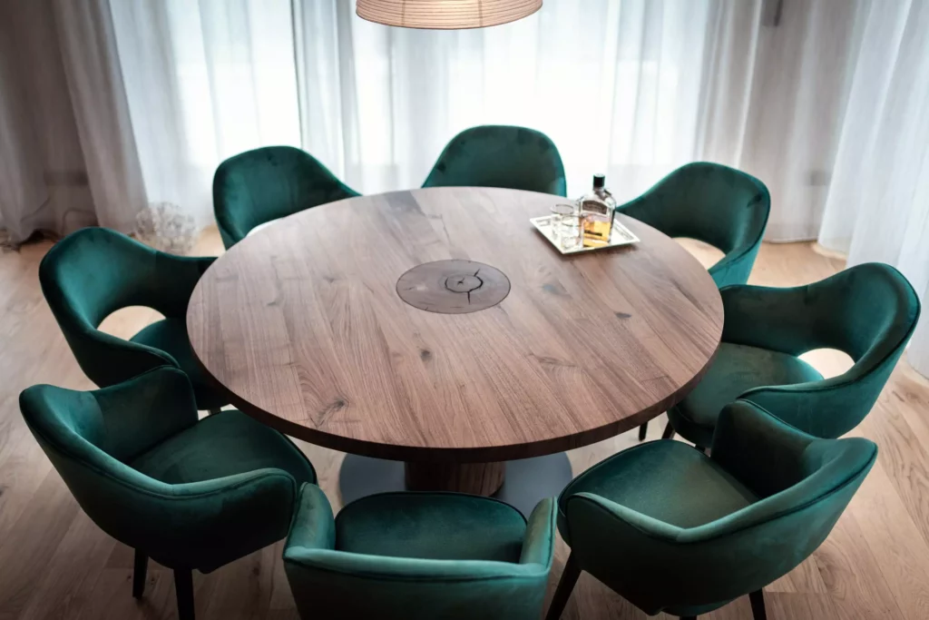Runder Esstisch aus Holz von Riva1920 mit acht grünen Samtstühlen in modernem Wohnraum mit Tageslicht und