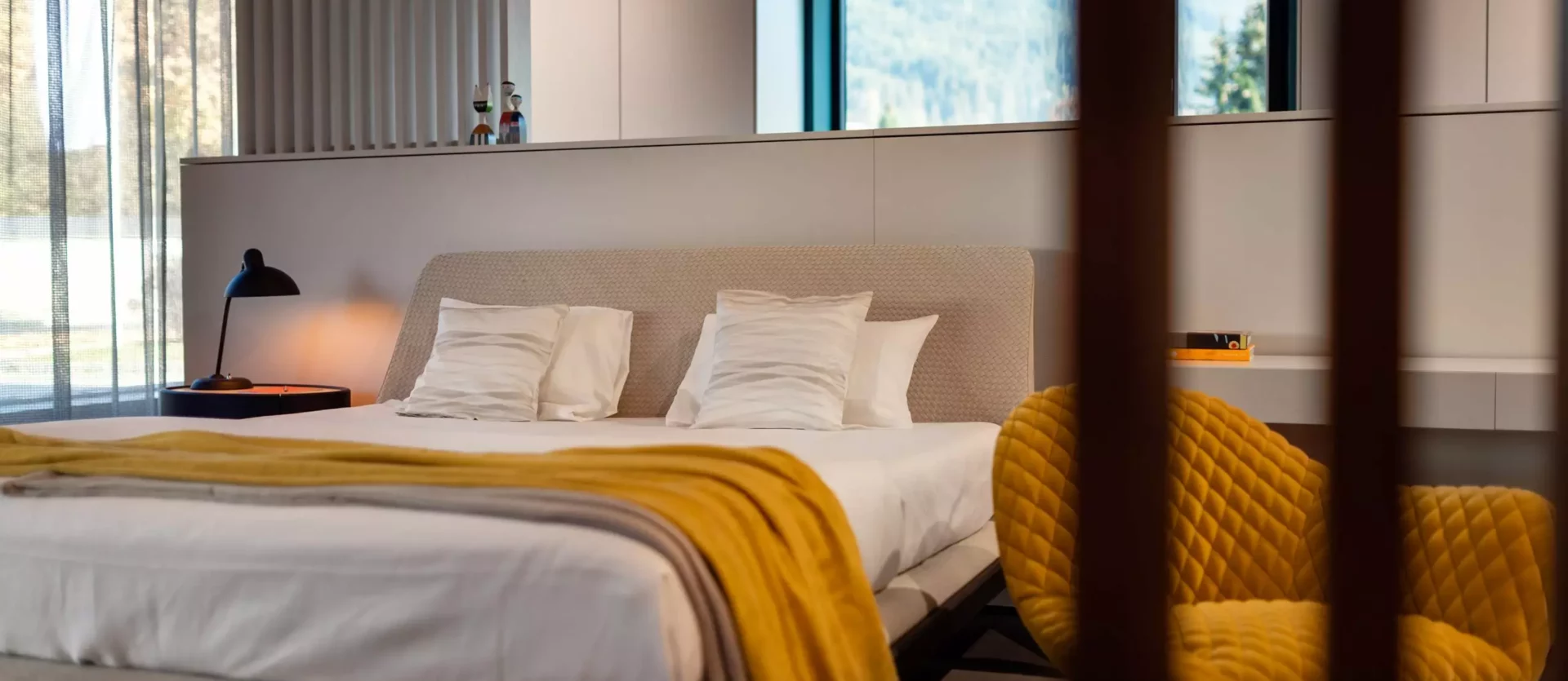 Modernes Schlafzimmer mit Minotti Bett, gelbem KFF Sessel, Poliform Lampentisch und maßgefertigten Möbeln in hellem Design