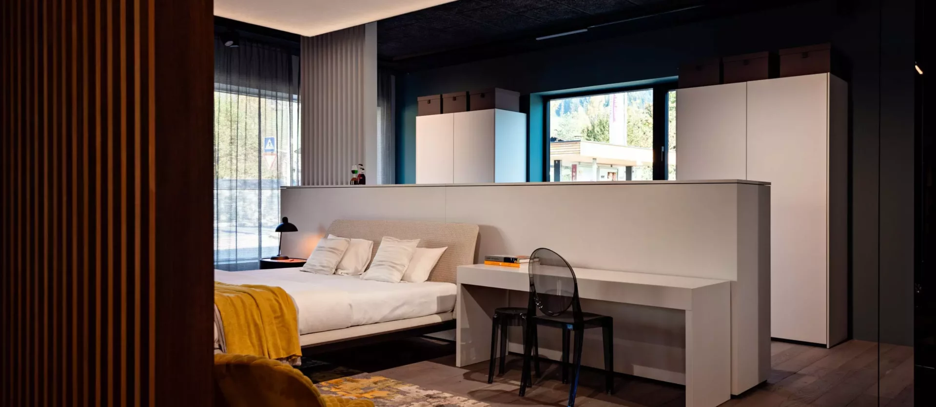 Modern eingerichtetes Schlafzimmer mit Minotti Bett, Poliform Schreibtisch, transparentem Stuhl, Teppich und maßgefertigten