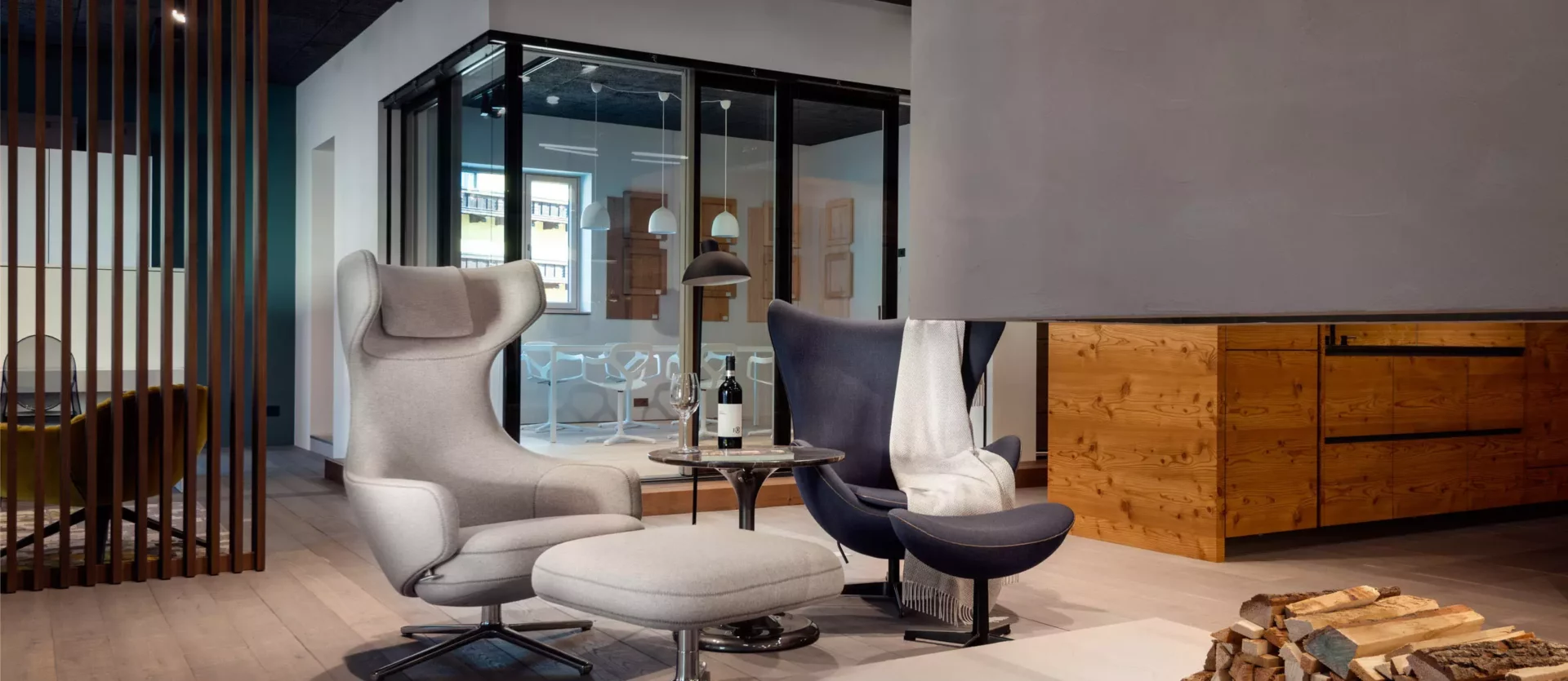 Moderner Wohnraum mit Minotti Sesseln, Poliform Hocker, Kamin mit Holzstapel, Tischlerei-Massivholzmöbeln und