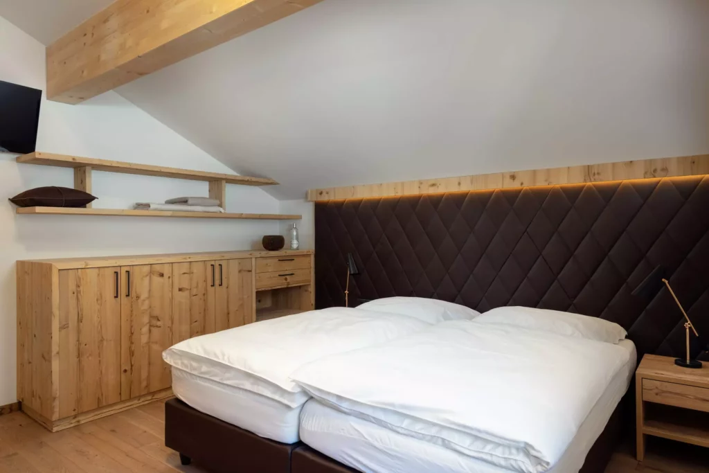Schlafzimmer mit maßgefertigtem Altholz-Sideboard, gepolstertem Kopfteil und modernem Design in Chalet Montis Flachau
