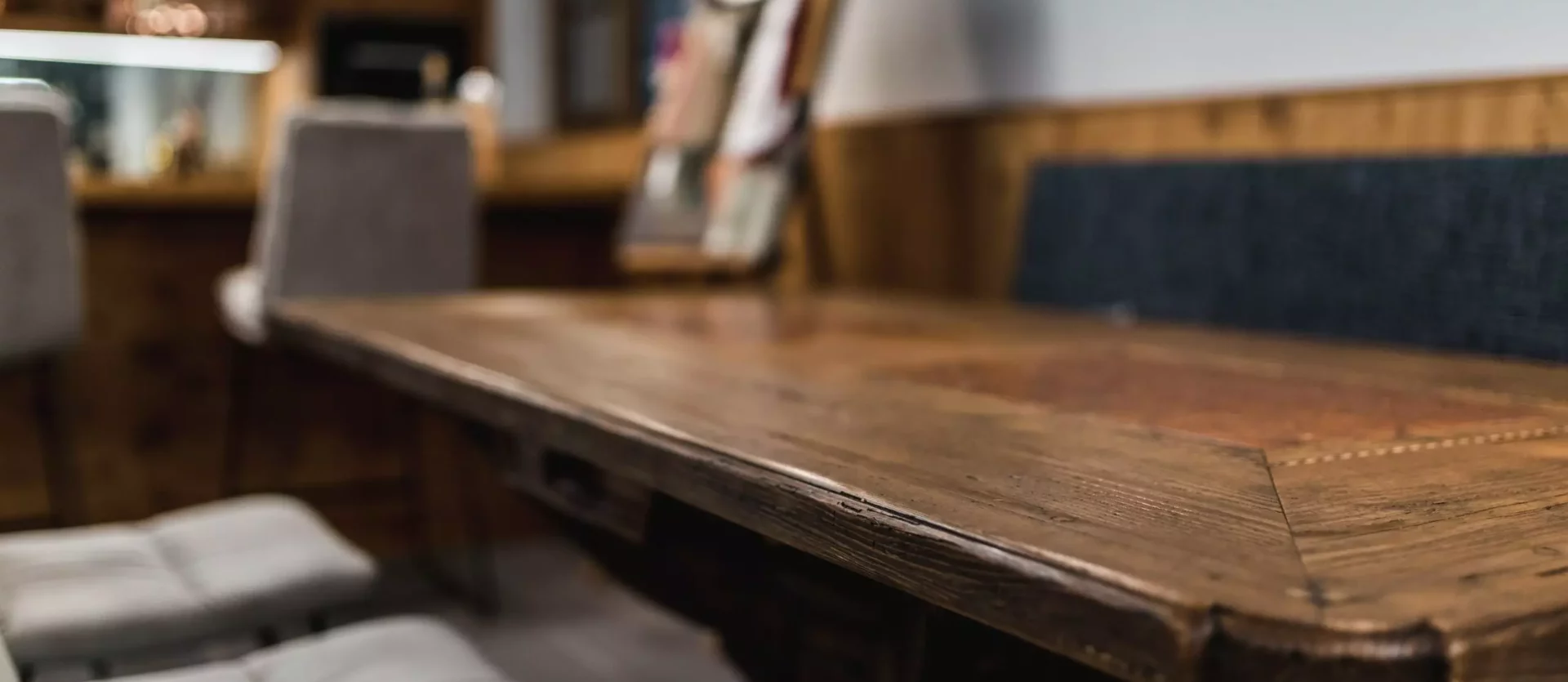 Nahaufnahme eines rustikalen Holztisches mit gepolsterten Stühlen und einer gepolsterten Bank in einem, Poliform