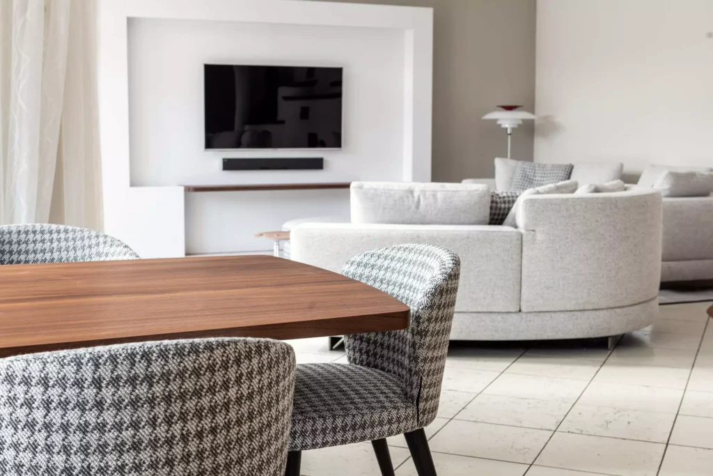 Moderner Wohnraum mit Minotti Designermöbeln, maßgefertigtem Holztisch, gemusterten Stühlen, Teppich und Vorhängen in hellem