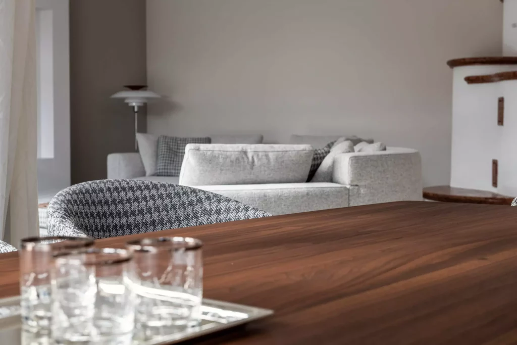 Moderner Wohnraum mit grauem Minotti Sofa, gemusterter Polsterstuhl, Holztisch und transparenten Gläsern auf Tablett vor