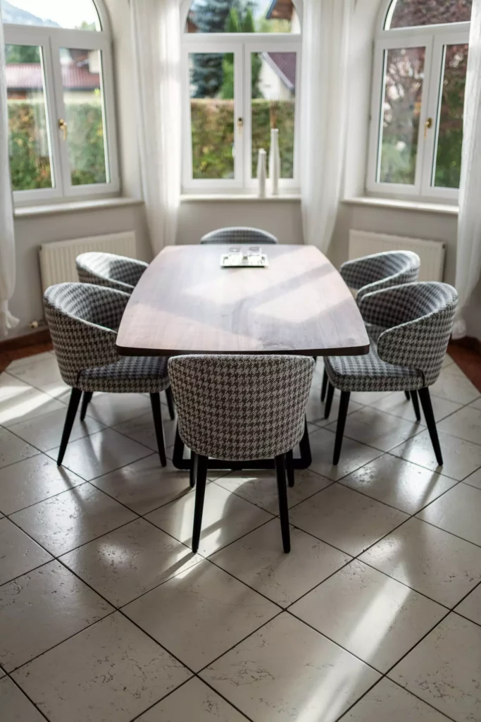 Esszimmer mit Minotti Designermöbeln, maßgefertigter Holztisch und gepolsterten Stühlen vor großen Fenstern mit weißen