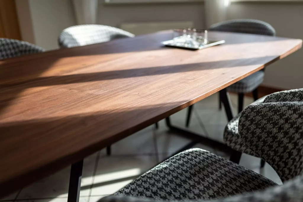 Moderner Minotti Esstisch aus Holz mit gepolsterten Stühlen im Hahnentritt-Muster in einem hellen Raum mit Vorhängen und