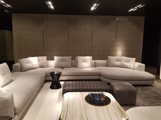 Moderner Minotti Wohnbereich mit grauem Ecksofa, Beistelltisch, gepolstertem Hocker und dekorativer Wand im Showroom Salzburg