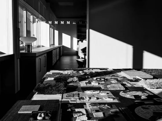 Modellübersicht mit Materialmustern und Raumkonzepten auf Tisch im Minotti Showroom Salzburg mit Sonnenlicht und Schatten