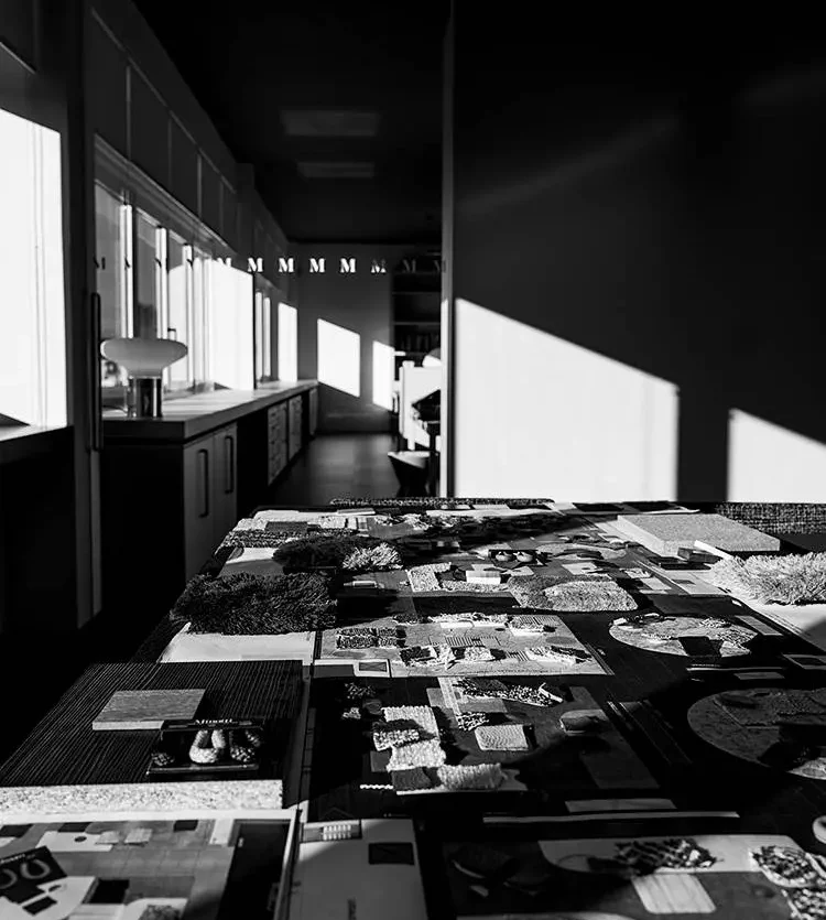 Modellübersicht mit Materialmustern und Raumkonzepten auf Tisch im Minotti Showroom Salzburg mit Sonnenlicht und Schatten