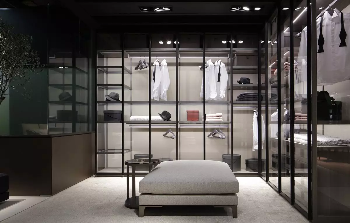 Moderne begehbare Poliform Garderobe mit Glasfronten, weißen Hemden, schwarzen Hüten, grauem Polsterhocker und integriertem