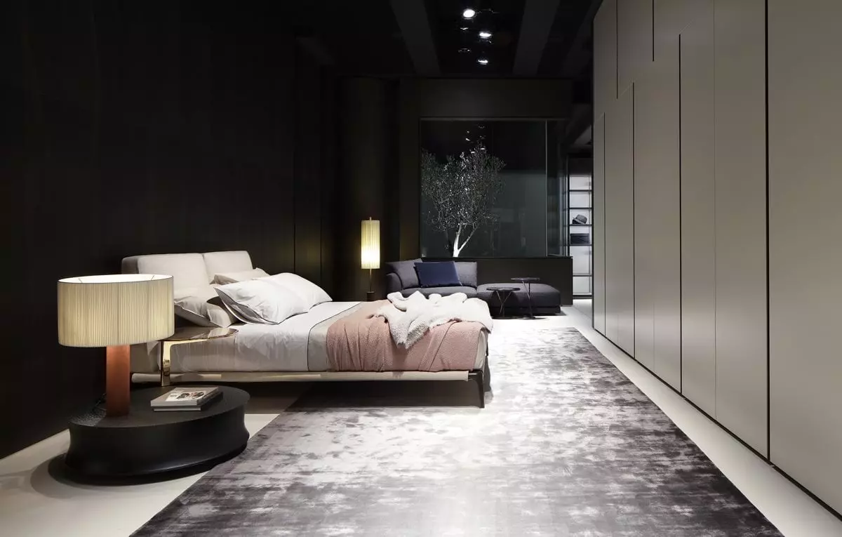 Modernes Schlafzimmer mit Poliform Bett, beigem Kopfteil, rosa Decke, grauem Teppich, Sideboard mit Lampe und Sitzbereich im