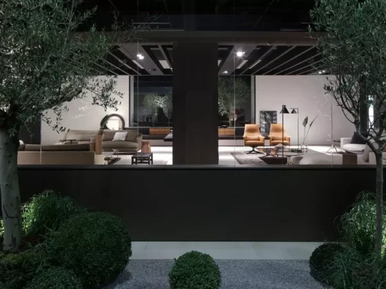 Blick durch Fenster auf modernes Wohnzimmer mit Poliform Designermöbeln, Ledersesseln, Sofas und Pflanzen bei Möbelmesse