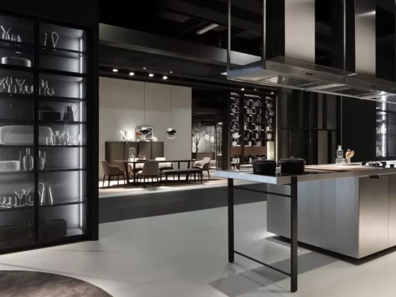 Moderne Poliform Kücheninsel mit Kochfeld und Dunstabzug, daneben Essbereich mit Designermöbeln und beleuchteten Vitrinen