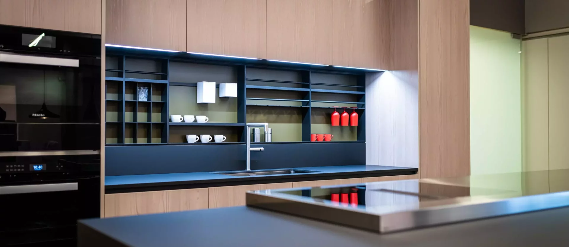 Moderne Poliform Küche Alea mit Lärchenholzfronten, schwarzer Arbeitsplatte, Induktionskochfeld und offenem Regal im