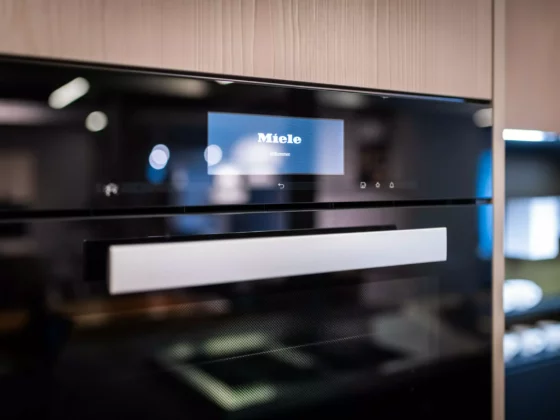 Moderne Poliform Küche mit Miele Backofen und Touchdisplay in hellem Holz und schwarzem Glas im Möbelstudio Showroom