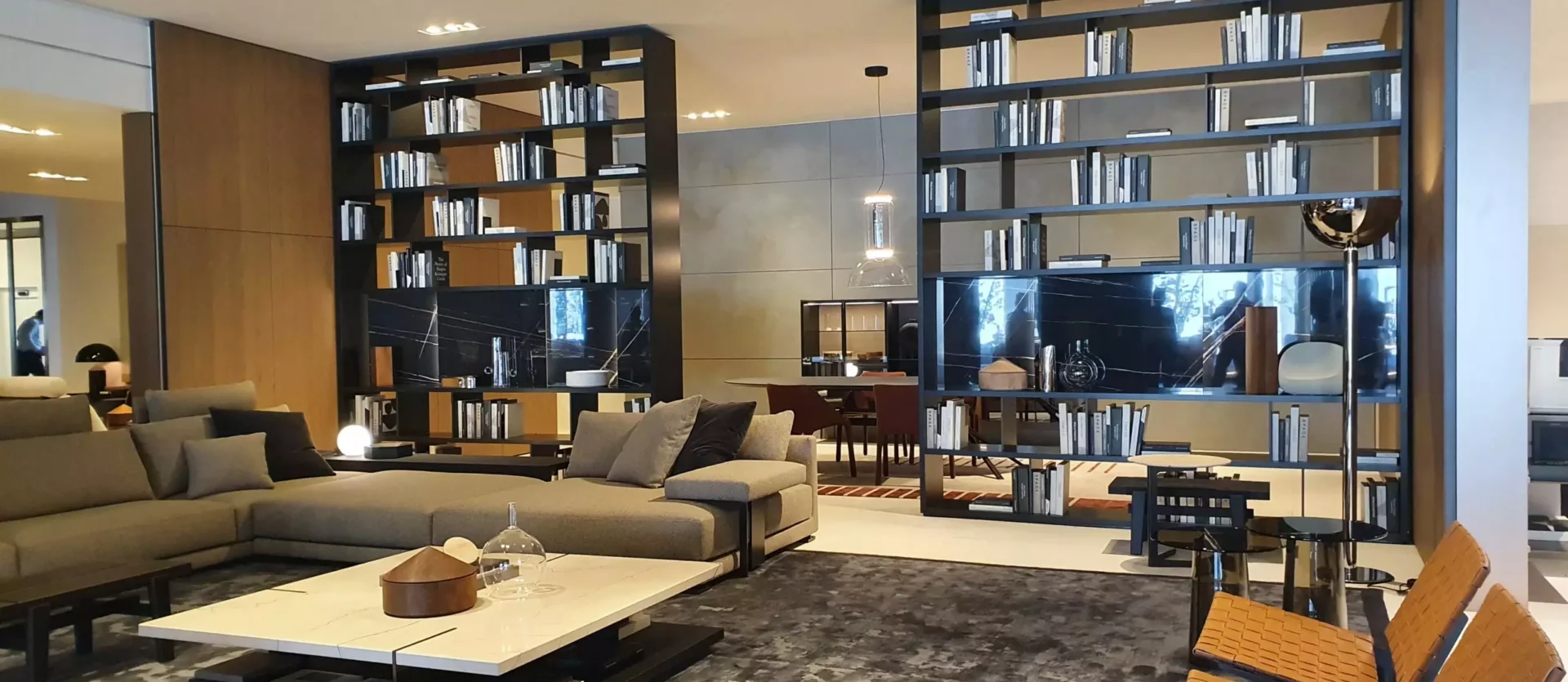 Modernes Wohnzimmer mit Poliform Sofa, großem Couchtisch, zwei Ledersesseln und offenen Regalen als Raumteiler in einem