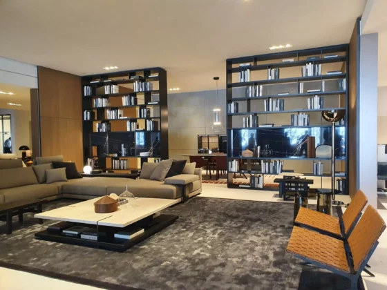 Modernes Wohnzimmer mit Poliform Sofa, großem Couchtisch, zwei Ledersesseln und offenen Regalen als Raumteiler in einem