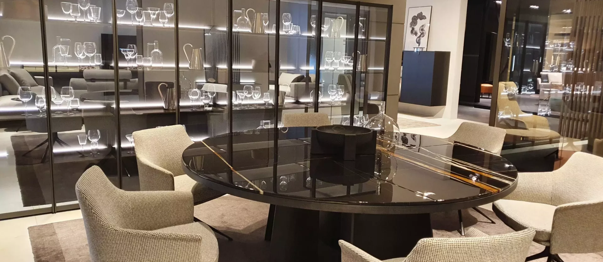 Moderner Poliform Essbereich mit rundem schwarzem Glastisch und sechs gepolsterten Stühlen vor beleuchtetem Vitrinenschrank