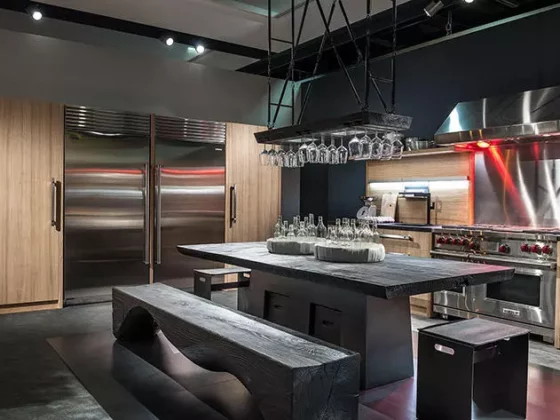 Moderne Küche mit massivem Riva1920 Holztisch, passender Bank, Edelstahlgeräten und Hängeregal für Gläser im Möbelstudio