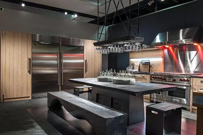 Moderne Küche mit massivem Riva1920 Holztisch, passender Bank, Edelstahlgeräten und Hängeregal für Gläser im Möbelstudio