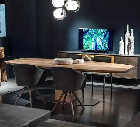 Moderner Riva1920 Massivholztisch mit zwei Stühlen in elegantem Möbelstudio mit dunkler Wand und Designbeleuchtung