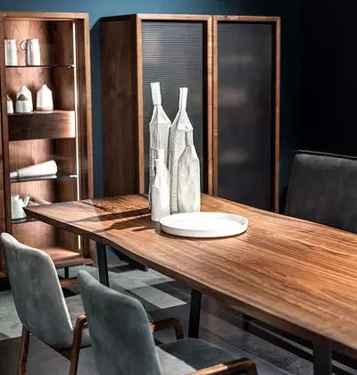 Massivholztisch von Riva1920 mit grauen Stühlen, dekorative Flaschen und Teller, modernes Möbelstudio mit Vitrinen und