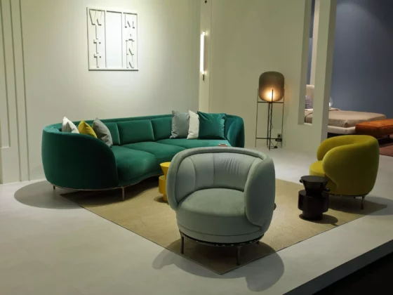 Modernes Wohnzimmer mit grünem Wittmann Sofa, zwei Sesseln in Hellgrün und Gelb, Teppich und Stehlampe im Möbelstudio