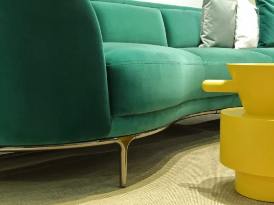 Grünes Wittmann Sofa mit Metallfüßen und gelbem Design-Beistelltisch auf Teppich im Möbelstudio Showroom