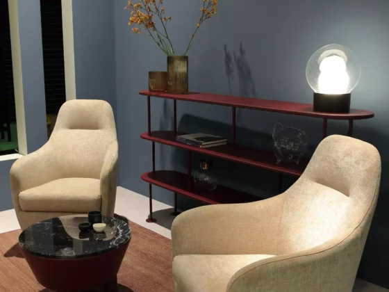 Gemütliche Sitzecke mit zwei beigen Polstersesseln, rundem Couchtisch mit schwarzer Marmorplatte und rotem Regal, Wittmann