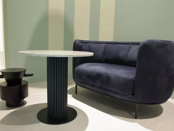 Dunkelblaues Sofa mit Samtbezug neben rundem Marmor-Tisch mit schwarzem Säulenfuß und skulpturalem Beistelltisch, Wittmann