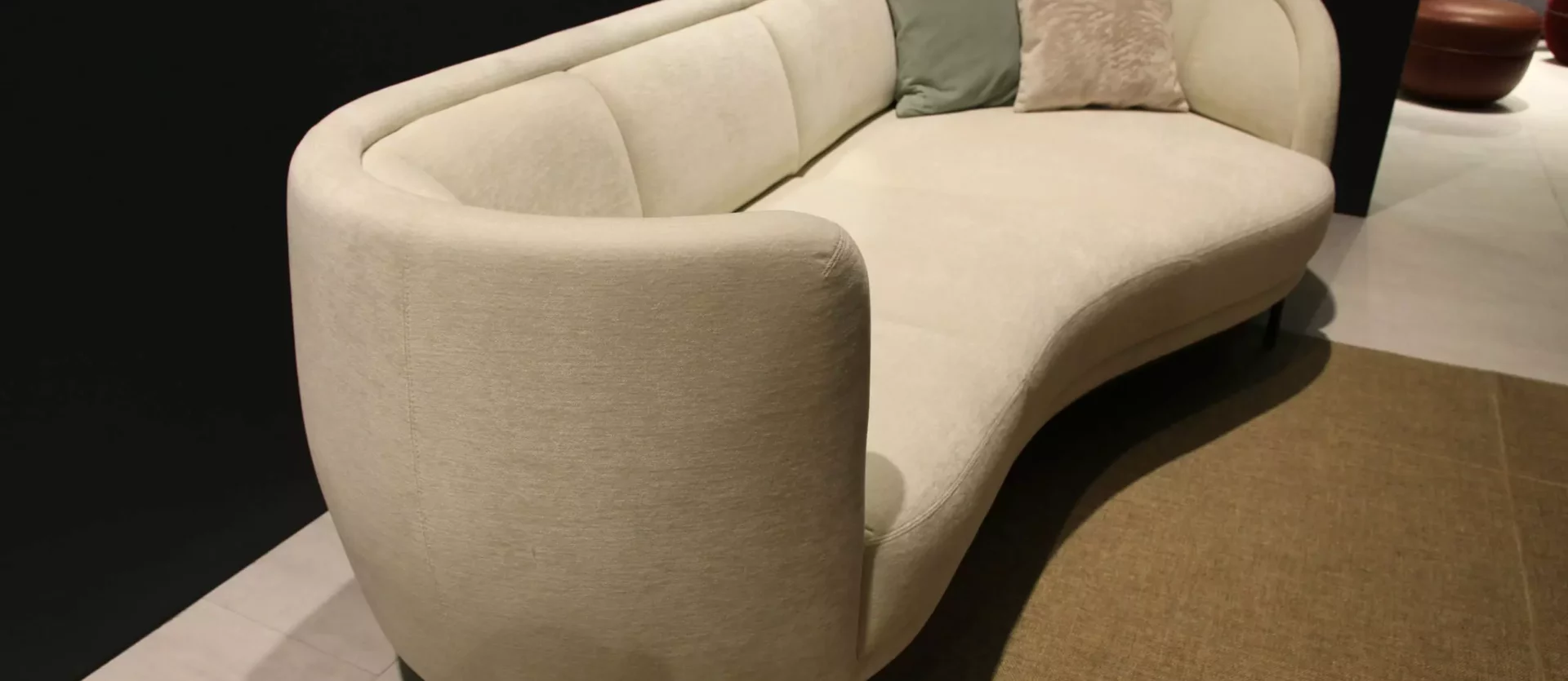 Beiges, geschwungenes Sofa von Wittmann mit zwei Kissen in modernem Showroom für Innenarchitektur und Designermöbel