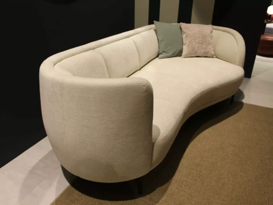 Beiges, geschwungenes Sofa von Wittmann mit zwei Kissen in modernem Showroom für Innenarchitektur und Designermöbel