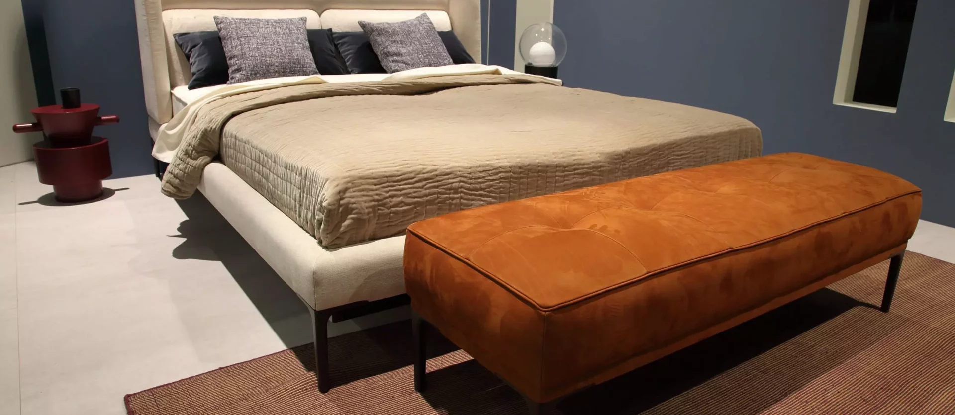 Beiges Wittmann Boxspringbett mit gepolstertem Kopfteil, braune Sitzbank am Fußende, modernes Schlafzimmer-Design